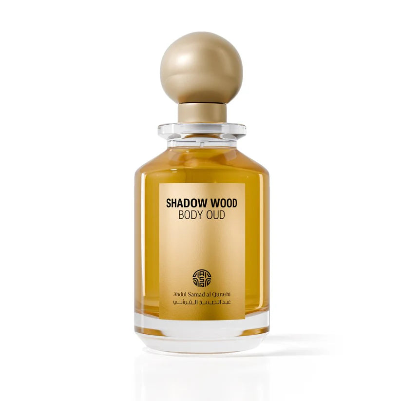 Abdul Samad Al Qurashi Shadow Wood Body Oud 100ml parfum bottle with rich golden oil, a matching gold label, and a spherical gold cap on a neutral background.